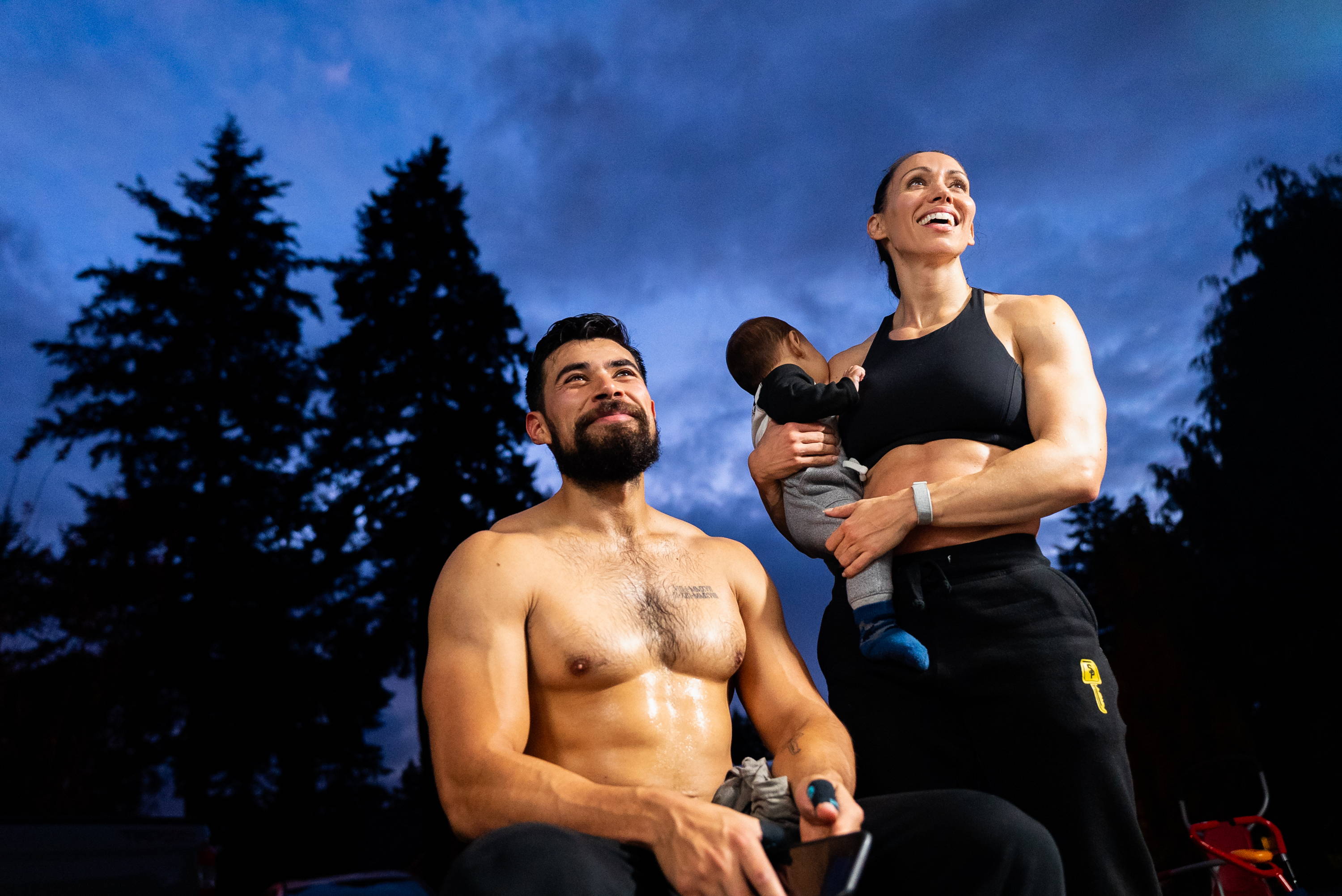 Fit couple with child holding workout equipment outdoors at dusk